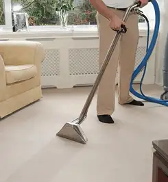 Professional carpet cleaner using a hot-water extraction wand and hose machine in a living room in Springfield, MO.