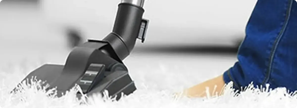 Close-up of a professional vacuuming a white carpet in Bois D Arc.